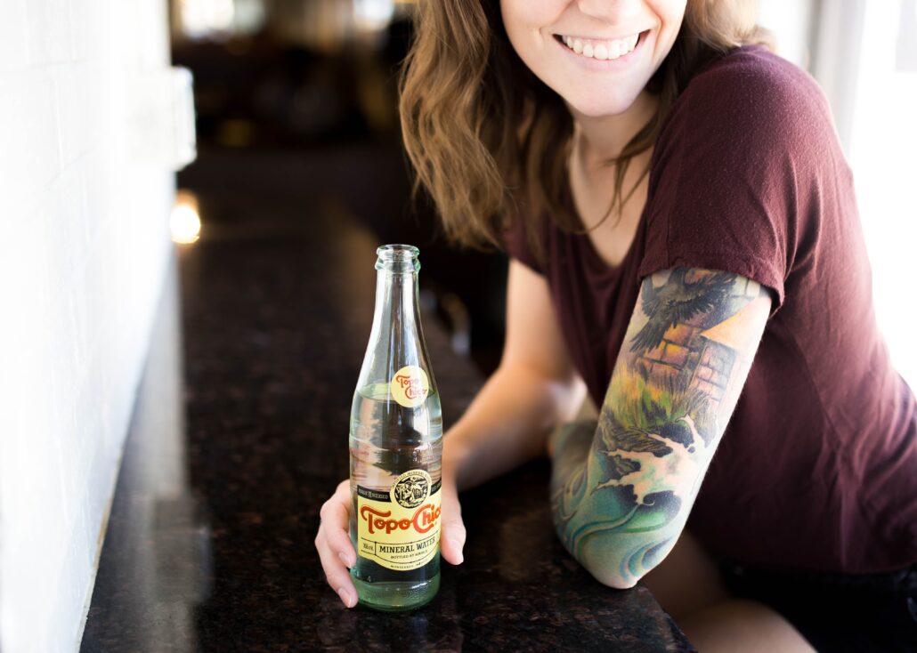 Mujer joven con tatuajes tomando un refresco