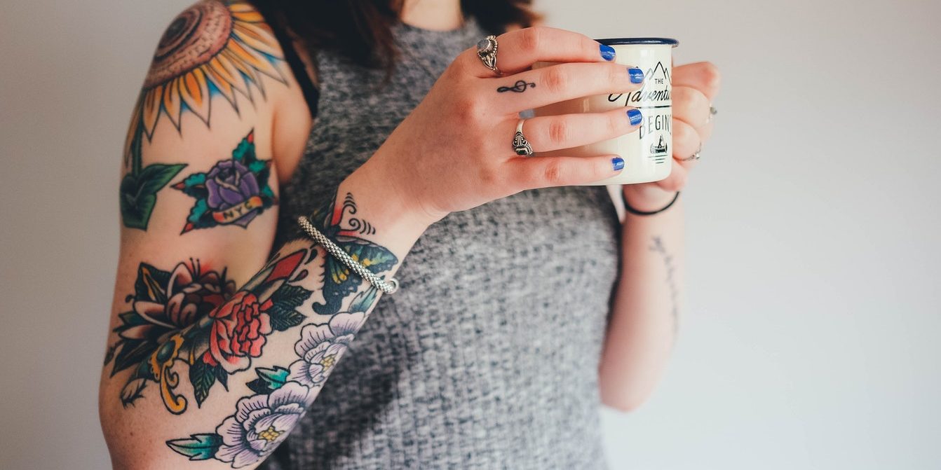 Mujer joven con tatuaje y café
